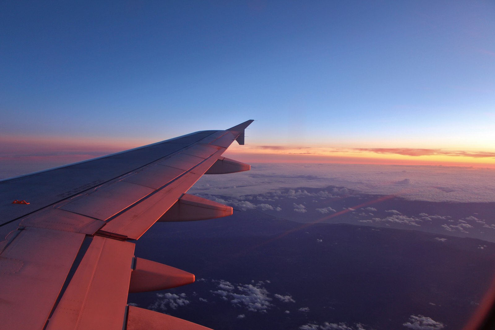Airplane wing above the clouds at sunset