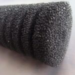 Close-up of a coarse black aquarium sponge filter foam showing its open pores