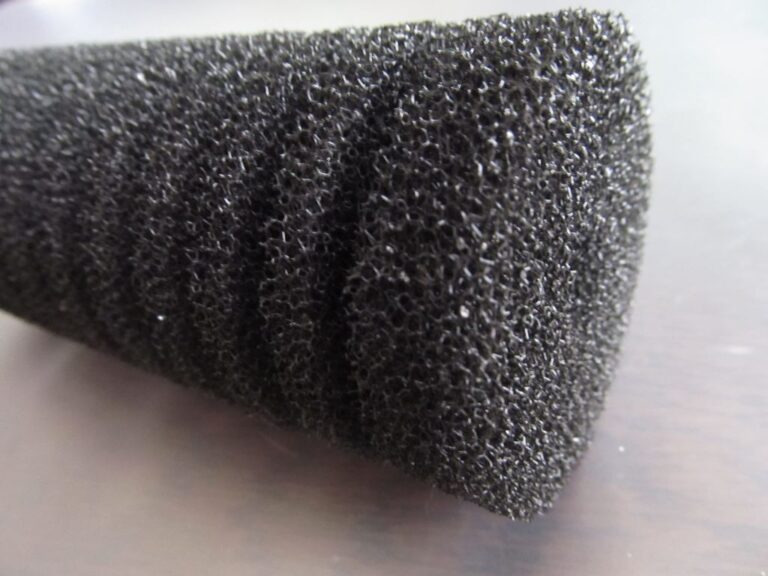 Close-up of a coarse black aquarium sponge filter foam showing its open pores